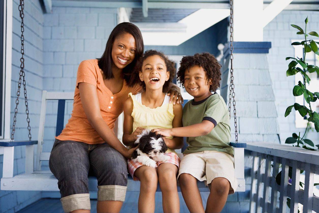 A woman and two children sitting on a porch swing.